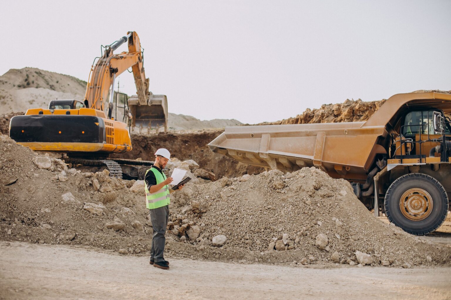 Chef de chantier devant une pelleteuse en carrière, assurance bris de machines et engins
