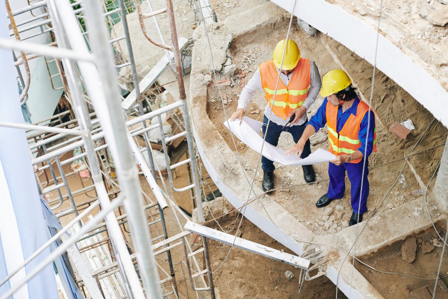 Conducteurs de travaux consultant des plans sur un chantier, pilotage de sinistres construction